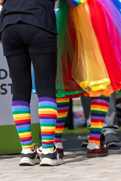 Two participants wearing rainbow striped socks and colorful pride clothing stand together at CSD event in Magdeburg. Multicolor fashion symbolizes LGBTQ visibility, diversity, equality and solidarity