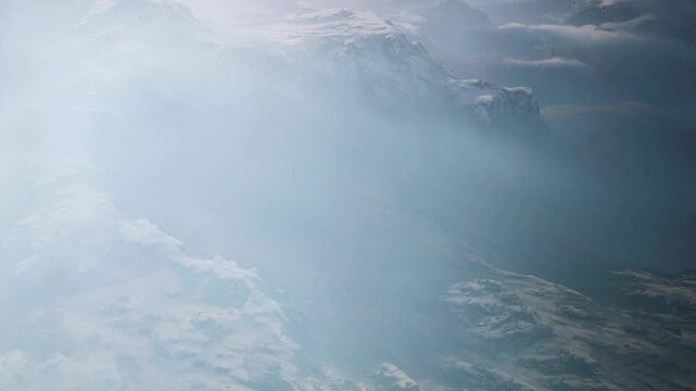 The scene shows snow covered mountains shrouded in fog early in the morning. The landscape is vast and remote with peaks rising into the sky.
