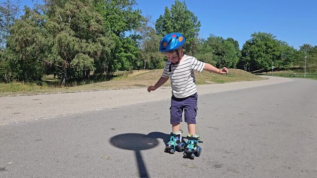 A cheerful boy in a striped shirt and blue helmet glides on rollerblades across a sunlit street, surrounded by lush green trees and a clear blue sky