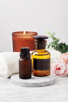 Essential oil bottles and scented candle on marble table with towel and flower,  spa concept