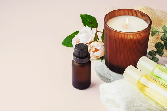 Essential oil bottle with aroma candle, white towel and pink rose, spa concep