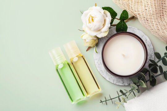 Spa background with aroma candle, body oil bottles and flower on green background