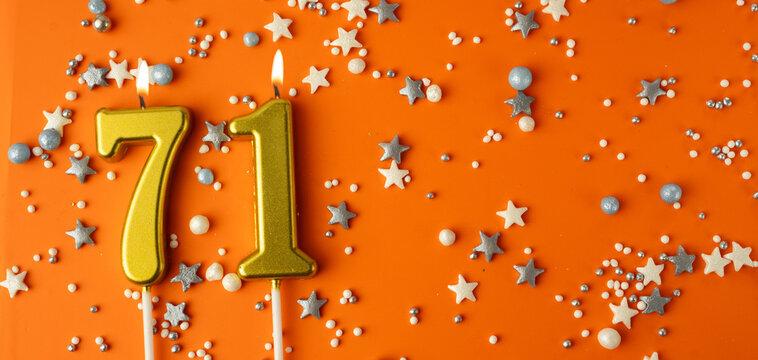 Birthday or anniversary celebration concept. Candles in the shape of the number seventy-one on an orange background among decorative ornaments. 71st anniversary. Banner