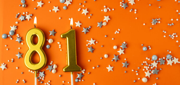 Birthday or anniversary celebration concept. Candles in the shape of the number eighty-one on an orange background among decorative ornaments. 81st anniversary. Banner