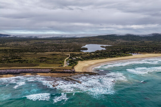Aerial view of Lake Arragan Beach and campground on the NSW North Coast, featuring the sandy shoreline, coastal camping area, native bushland and Pacific Ocean within Yuraygir National Park
