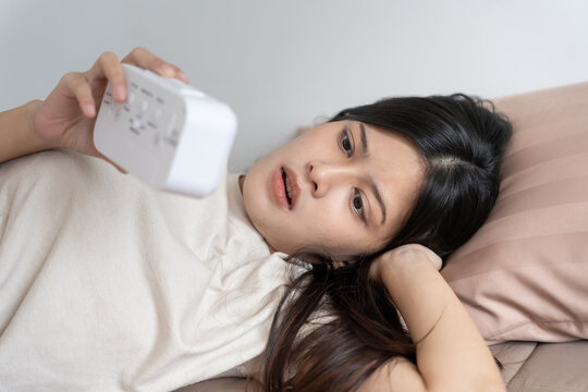 Shocked Asia young woman looking at clock alarm, lady is late appointment or work or class study, overslept, difficulty get up in mornings, time worried, not on time, sleepy, over due, Hurry up time