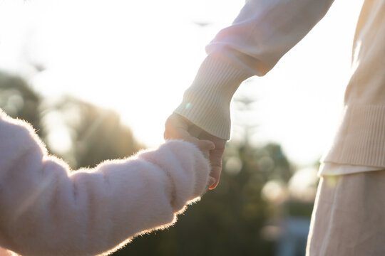 Mother and daughter holding hands outdoors, Mom hand lead his kid walking together. Family. Childhood development and growth with love for child, caring mom, happy family kid dream, support