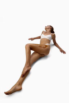Relaxed woman laying on the floor with wax applied along upper thigh. Concept of wax treatment, leg epilation, beauty results, beauty service, waxing products, salon promotion.