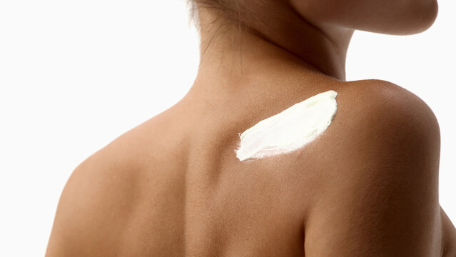 Closeup of moisturizing cream applied to woman shoulder. Concept of shoulder care, body moisturizer, healthy skin, cosmetic advertising, daily skincare.