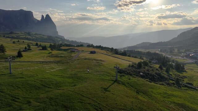 Aerial Drone View of Alpe di Siusi Alpine Meadow with Sciliar Peaks and Dramatic Sunrays, Italy