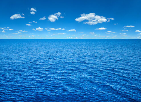 clouds on blue sky over calm sea with sunlight reflection
