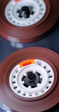 Rotating Magnetic Tape Reels in Extreme Close-Up. Brown audio tape spins around two exposed white hubs inside a cassette mechanism