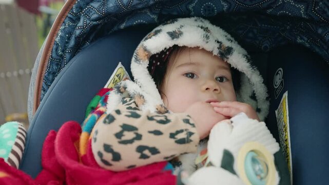 Baby Sucking Fingers in Hooded Outfit and Car Seat