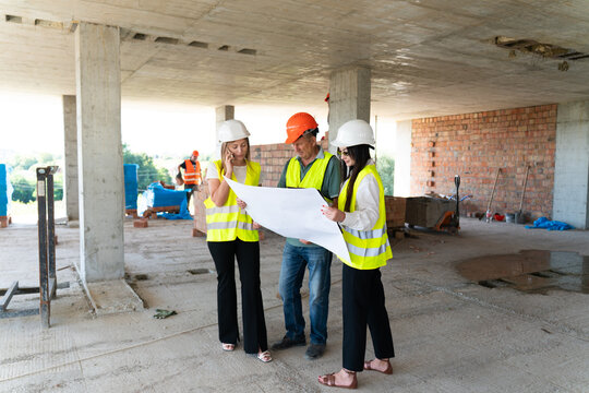 Woman engineers and builder study building layout paper. Large document allows to review important project features and construction details