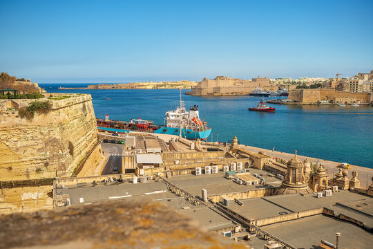 Scenic view old fortress bastions vessel moored seaport harbor stone architecture blue sea water background. Malta, Valletta.