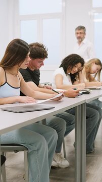 University professor helping students during a classroom exam