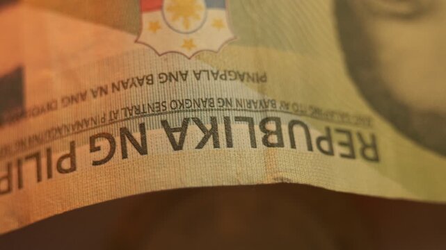 Macro shot of a Philippine peso coin resting on a banknote.