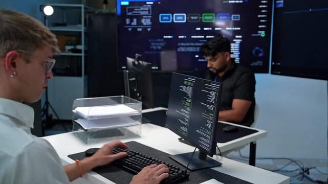 Two programmers collaborating in a modern tech environment with multiple screens displaying code and data analysis