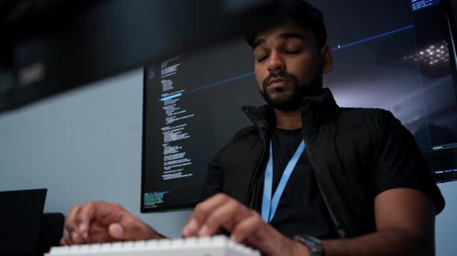 Tired software developer coding at desk during late night hours in contemporary office setting