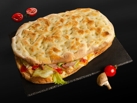 Folded Pizza Sandwich with Meat, Lettuce and Cheese on Slate Board