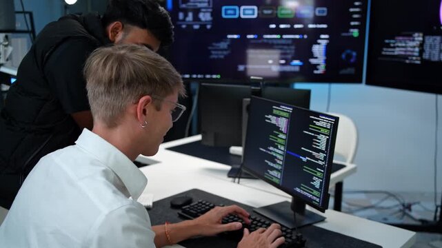 Dedicated software developer working on intricate coding projects with two screens in a contemporary office setting