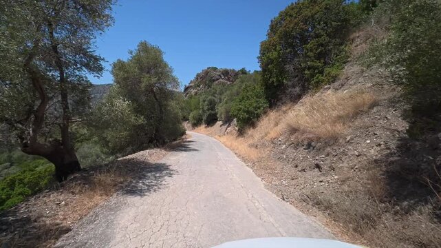 A car drives slowly along a dangerous winding mountain road on the island of Crete, Greece.