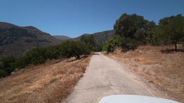 A car drives slowly along a dangerous winding mountain road on the island of Crete, Greece.
