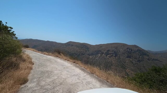 A car drives slowly along a dangerous winding mountain road on the island of Crete, Greece.