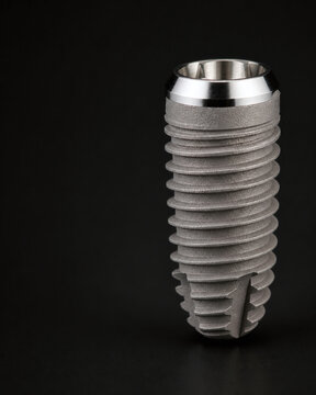 Macro dental implant fixture on dark background