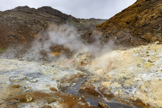 View of steam rising from the colorful mineral deposits and rocky volcanic landscape of the Seltun Geothermal Area in Grindavik, Hafnarfjardarkaupstad, Iceland.