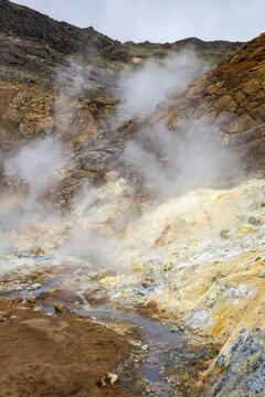 View of Seltun Geothermal Area with steaming vents, colorful mineral deposits, and rugged volcanic rocks in Grindavik, Hafnarfjardarkaupstad, Iceland.