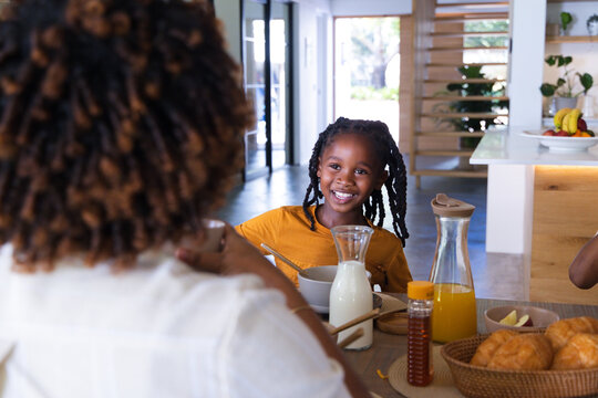 African American family sharing breakfast at home, child wearing orange shirt smiling