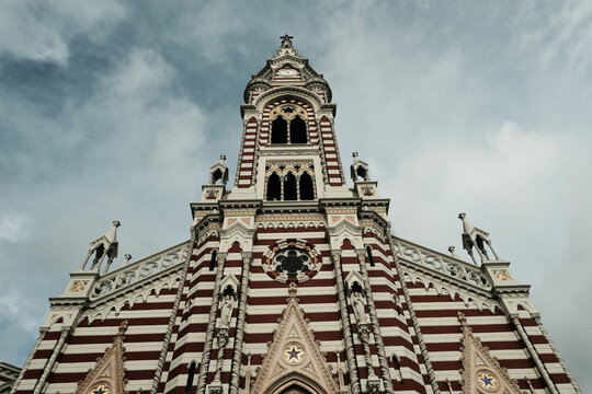 View of the Iglesia de Nuestra Senora del Carmen featuring its distinctive red and white striped facade, intricate gothic architecture, and towering steeple in Bogota, Bogota, Colombia.