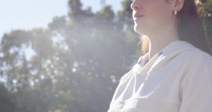 Woman meditating, breathing, lifting chin toward sun, sun drawing gaze showing watch mic