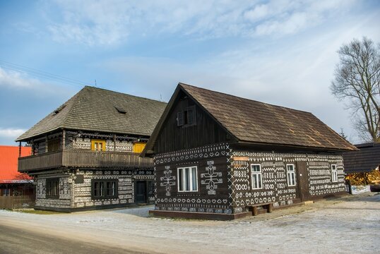 Traditional dark wooden cottages adorned with white ornamental geometric paintings, showcasing well-preserved Slovak folklore and rural cultural heritage in the historical village of Cicmany.