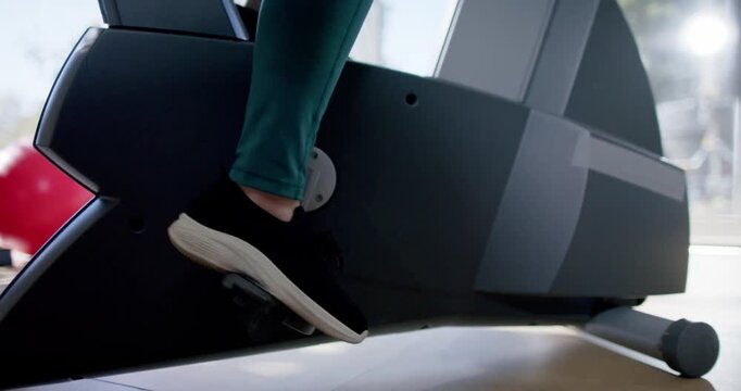 Lower leg and foot are initiating stroke, pressing bike pedal down to power cardio by window
