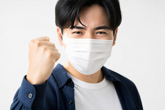 A young man wearing a white face mask is posing against a plain white background.