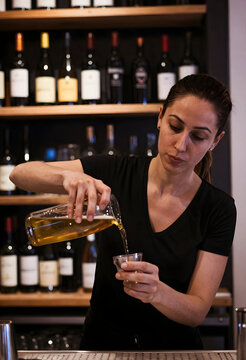 Hospitality industry and service, bartender pouring beer into a glass at a bar counter with wine bottles on shelves in the background