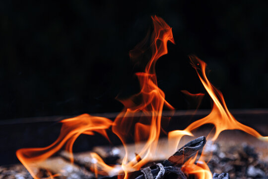 View of bright orange flames flickering over burning charcoal embers in a dark setting in Jhelum, Punjab, Pakistan.