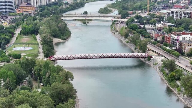 flying above Bow River next to Prince&rsquo;s Island Park towards Peace Bridge and Bow River Pathway, with parts of Downtown Calgary ( Alberta, Canada) on left side - 4k aerial video footage 