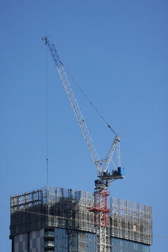 View of a construction crane atop a modern high-rise building against a clear blue sky in Parramatta, New South Wales, Australia.