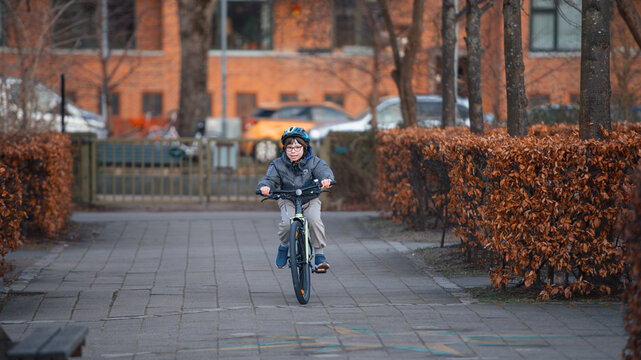 Joyful boy in a helmet rides his bicycle along an autumn path