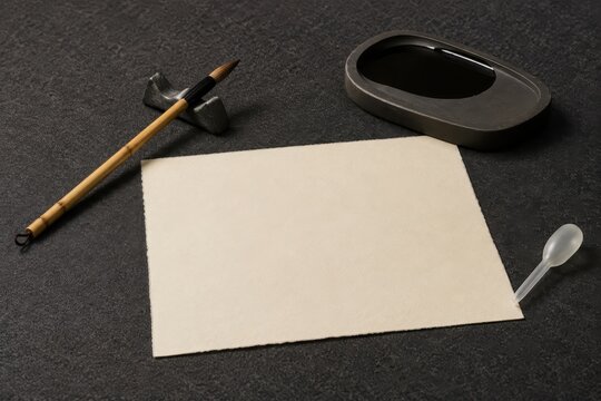 Calligraphy brush and ink stone beside a blank sheet of paper