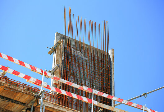 Reinforced concrete wall with dense rebar mesh grid and wooden formwork at construction site, industrial building structure under clear sky closeup