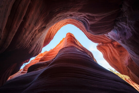 View of the smooth, undulating sandstone walls of a slot canyon in Grand Staircase-Escalante National Monument, with vibrant orange and red rock formations near Kanab, Utah, United States.
