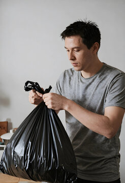 Household chores and waste management, man tying a black plastic garbage bag for disposal and recycling at home to maintain a clean living environment