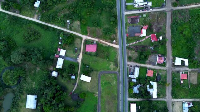 Top Down Drone View of Main Road Through Tropical Ecuador Countryside, Small Houses, Green Fields, Forest Patches and Rural Infrastructure