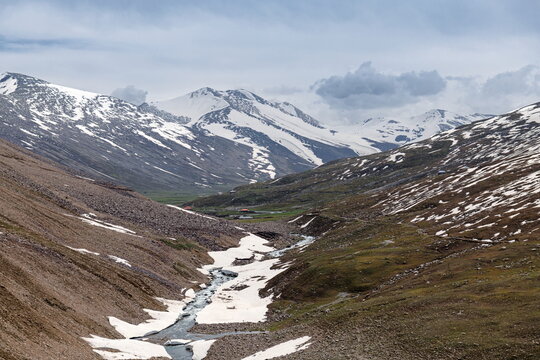 View of the snow-capped peaks and winding stream at Babusar Top in the mountainous landscape of Naran, Khyber Pakhtunkhwa, Pakistan.