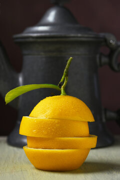 Lemon and Tea Pot Still Life. A sliced and stacked fresh ripe lemon in front of a tea pot.
