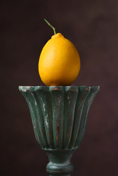 Lemon Still Life. A single fresh picked ripe lemon on a green pedestal